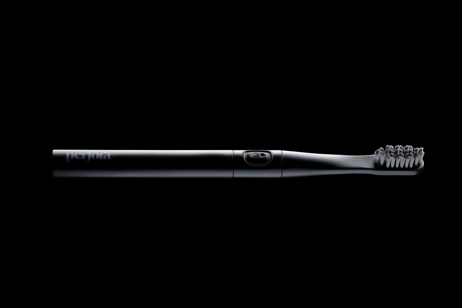 Black electric toothbrush with a power button, photographed on a black background.