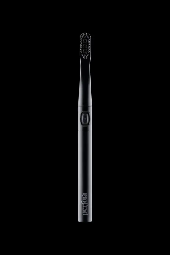 Black electric toothbrush with a power button on the handle against a black background.